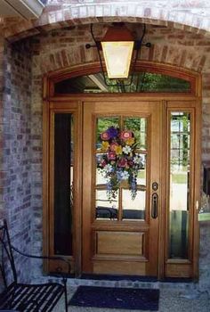 a wooden door with flowers on it and a bench in front of the entryway