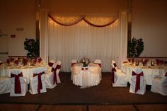 the banquet room is set up with white linens and red sashes on tables