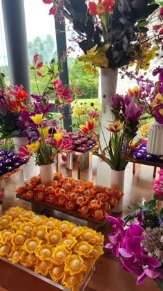 a table topped with lots of colorful flowers next to potted plants and vases