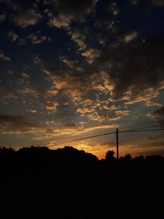 the sun is setting behind some power lines