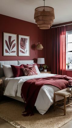 a bedroom with red walls, white bedding and two framed pictures on the wall