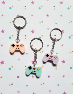 three different colored video game controllers keychains on a star patterned tablecloth with confetti