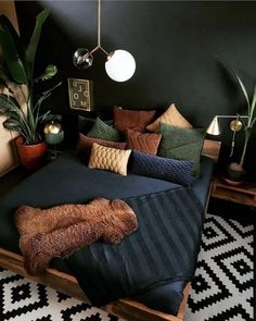 a bed with pillows and blankets on it in a room next to a table lamp