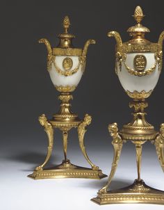 two gold and white vases sitting next to each other