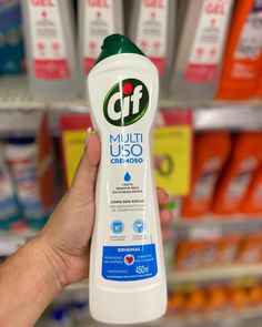 a person holding up a bottle of deodorant in front of some shelves