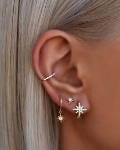 a woman with blonde hair wearing gold and white stars ear cuff earrings on her left ear