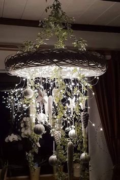 a chandelier hanging from the ceiling filled with plants and balls in front of a window