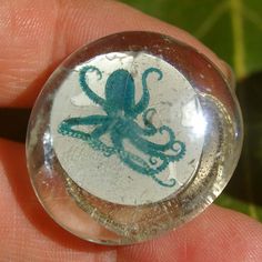 an image of an octopus in a glass ball on someone's finger with green ink