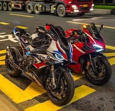 two motorcycles are parked on the side of the road in front of a red truck