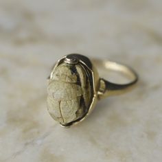 Antique Victorian era Egyptian Revival scarab ring set in 18k gold. The scarab is likely ancient as ancient elements were added to jewelry around this time. The scarab appears to be made from steatite stone. The setting has a lovely scalloped design.  Era: c.1890s Markings: None Materials: Steatite scarab, 18k gold  Ring Size: 6 (comes with one free resizing by our jeweler)  Weight: 4.4 grams  Head measures approx. 15mm x 9.5mm  Condition: Excellent antique condition with minor surface wear from Ancient Style Collectible Yellow Gold Rings, Ancient Oval Gold Rings, Art Deco Gold Oval Cabochon Ring, Gold Cat Ring, Scarab Ring, Deer Antler Jewelry, Antler Jewelry, Scalloped Design, Earring Kit