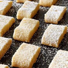 several square pieces of cake sitting on top of a baking sheet covered in powdered sugar