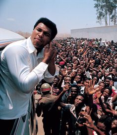 a man standing in front of a large group of people with his hand up to his face