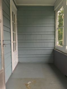 an empty porch with no furniture on the floor and one door open to another room