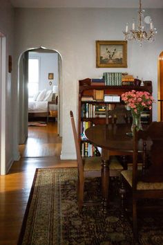 a dining room table and chairs in front of a bookshelf