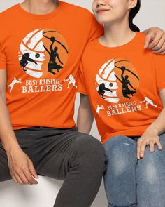 two people sitting next to each other wearing orange tshirts with basketball logos on them