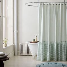 a white bath tub sitting next to a shower curtain in a bathroom under a window