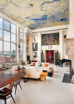 a living room filled with furniture and a fire place next to a large painting on the ceiling