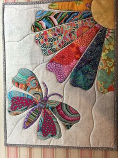 a quilted wall hanging with colorful butterflies on it