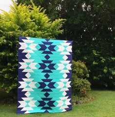 a blue and white quilt sitting on top of a lush green field