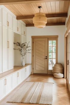 an empty room with white cabinets and wooden flooring is pictured in this image, there are two vases on either side of the door