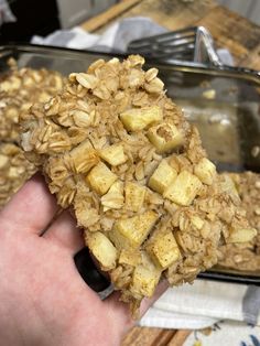 a person holding up a piece of granola in front of a tray of oatmeal