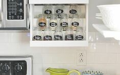 an open cabinet in the kitchen filled with jars and glasses next to a toaster oven