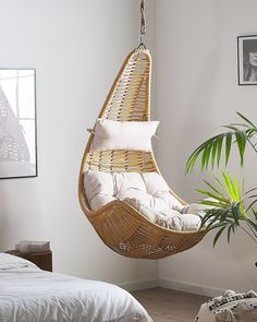 a bedroom with a bed and hanging chair in the corner next to a potted plant