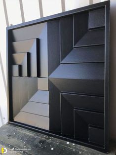 a large black box sitting on top of a wooden table next to a white wall