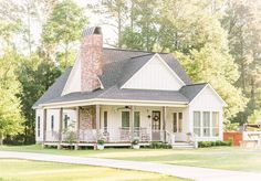 a white house with a brick chimney in the front yard