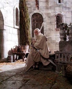 an old man sitting on a bench in front of a building