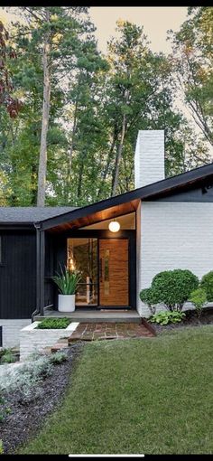 a modern house in the woods surrounded by trees and shrubs, with an entry way leading to the front door