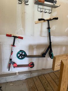 two scooters are hanging on the wall next to a bench and shelves with tools