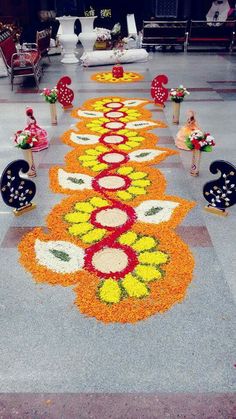 a long line of flowers on the ground with chairs and tables in the backround