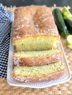 three slices of lemon zucchini bread on a white platter next to sliced cucumbers