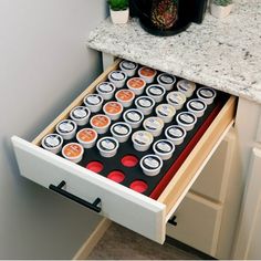 an open drawer in a kitchen with sushi and coffee cups on the bottom shelf