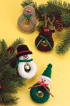 crocheted christmas ornaments are hanging from pine branches on a yellow background with evergreen needles