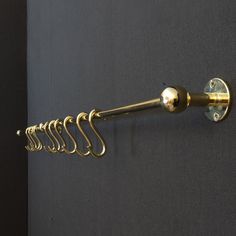 a gold towel rack is hanging on the wall next to a gray wall with several hooks