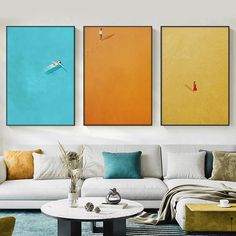 three paintings on the wall above a couch in a living room with blue and orange accents