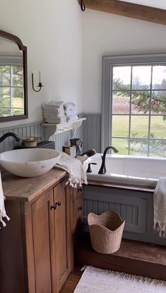 a bathroom with a sink, mirror and tub in it's corner next to a window