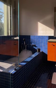 a bathroom with blue tiles and orange cabinets