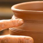 a close up of a clay pot with a finger on it's tip and another hand touching the top