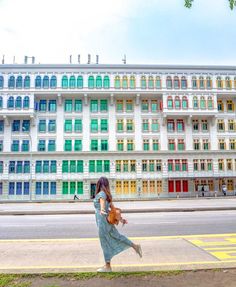 a woman is walking down the street in front of a building with multicolored windows