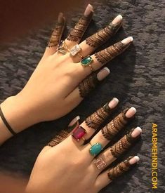 two hands with henna tattoos and rings on them