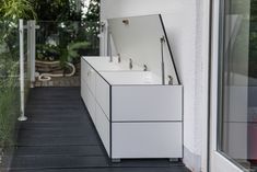 a white sink sitting on top of a wooden floor next to a window covered in plants