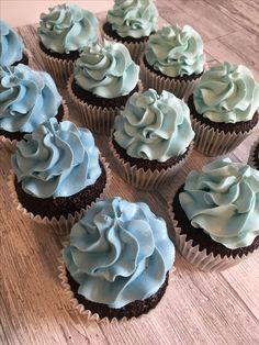 cupcakes with blue frosting sitting on a wooden table