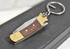 a knife shaped keychain is sitting on top of a black case