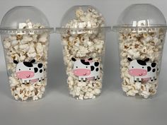 three plastic containers filled with popcorn that have animals on them, and one has a cow painted on it