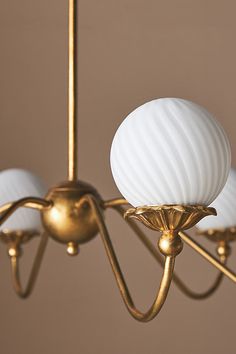 a chandelier with three white lamps hanging from it's arms and two gold fixtures