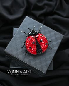 a ladybug brooch sitting on top of a black box with red beads