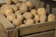 a crate filled with potatoes sitting on top of a wooden table